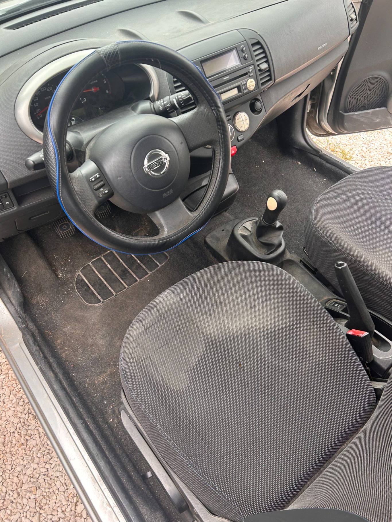 Intérieur d'une voiture avec un volant, un levier de vitesses et des sièges en tissu.